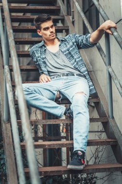 Loft merdivenlerde oturan kot modelde şık delikanlı. Ateş moda