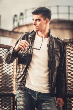 Şık delikanlı model deri ceket ve güneş gözlüğü poz.