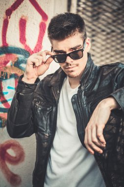 Şık delikanlı model deri ceket ve güneş gözlüğü poz.