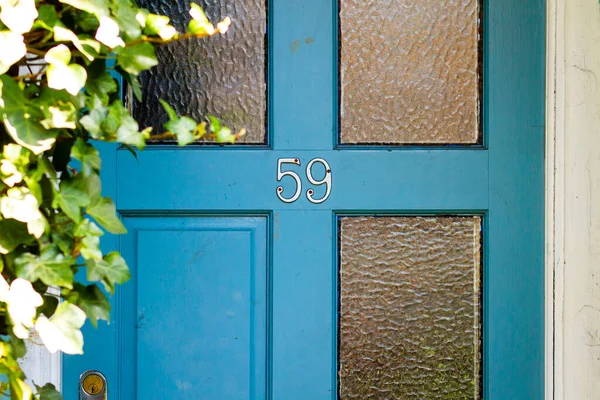 59 numara, cam panelli eski ahşap bir ön kapıda.
