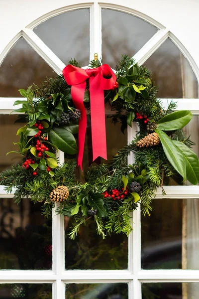 Beyaz ahşap ön kapıda yeşil bir Noel çelengi