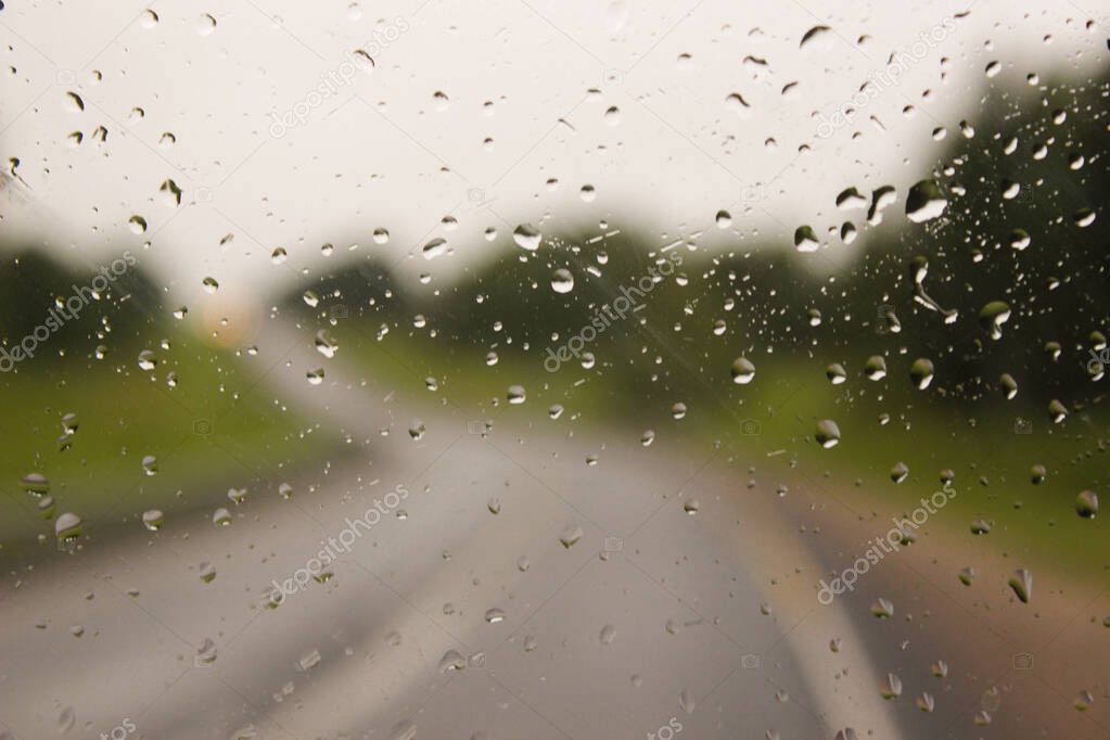 Drops of water from rain on a machine glass. Bad visibility. Caution when operating the machine. Driving in bad weather. Inadequate visibility. Dangerous driving. Beautiful drops on the glass.