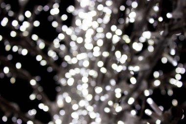 Arka plan için odaklanmış beyaz bokeh ışıkları - tatiller, dekorasyon ve parti konsepti. Gümüş ve beyaz bokeh ışıkları. Soyut duvar kağıdı. Siyah arkaplanda Bokeh ışıkları, koyu, bulanık dokuda.