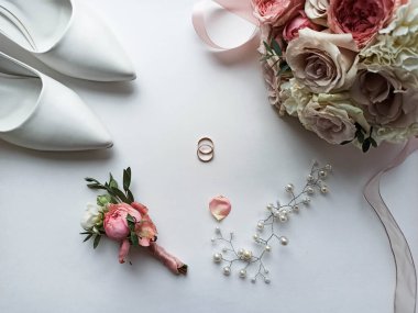 Pembe çiçekler, inci mücevherler ve beyaz arka planda iki altın alyans. Düğün konsepti. İzole edilmiş