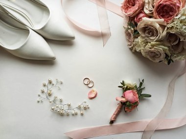 Pembe çiçekler, inci mücevherler ve beyaz arka planda iki altın alyans. Düğün konsepti. İzole edilmiş