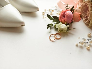 Pembe çiçekler, inci mücevherler ve beyaz arka planda iki altın alyans. Düğün konsepti. İzole edilmiş