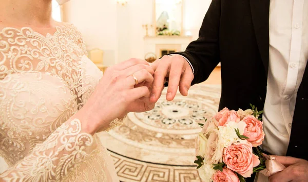 Wedding rings for engagement. A married couple exchange wedding rings at the wedding ceremony. The bride put the ring on her husband\'s finger. Details of the wedding concept. A happy family. Together
