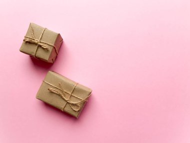 Pembe arka planda kraft kağıdına sarılı bir hediye kutusu. Yukarıdan görünüm, düz yatış, üst görünüm tasarımı. Minimalizm. Konsept satışlar, alışveriş, Noel tatilleri ve doğum günü.