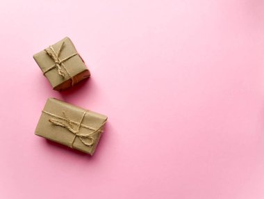 Pembe arka planda kraft kağıdına sarılı bir hediye kutusu. Yukarıdan görünüm, düz yatış, üst görünüm tasarımı. Minimalizm. Konsept satışlar, alışveriş, Noel tatilleri ve doğum günü.