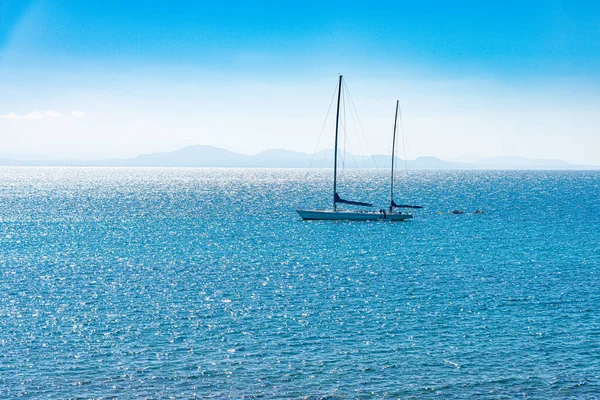 Güvertede tanınmayan mürettebatla Atlantik Okyanusu 'nda lüks bir yelkenli. Arkadaki Fuerteventura Adası. Lanzarote, Kanarya Adaları, İspanya. Seyahat yat macerası konsepti.