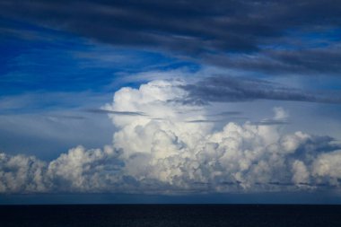 Okyanus sularının panoramik manzarası mavi gökyüzü arka planında dramatik kümülüs fırtınası bulutları çizgisi..