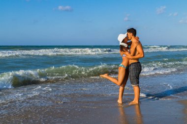 Sahilde bikinili ve şortlu çekici genç bir çift..