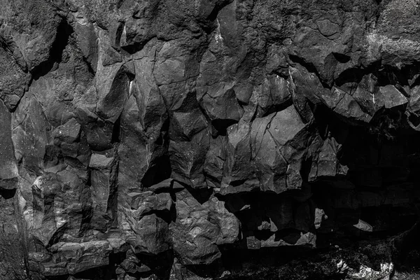 Volcanic rock relief structure black lava background texture.