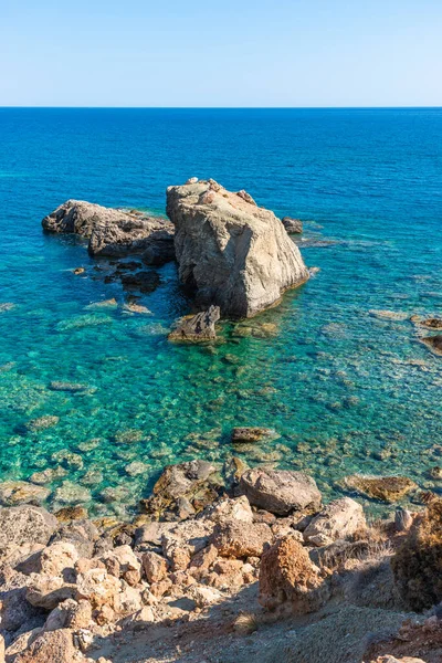 Křišťálově čisté tyrkysově modré oceánské vody. Jihovýchodní pobřeží s oblázkovými kameny a skalami, Grete Greece. Koncept cestovní dovolené. — Stock fotografie