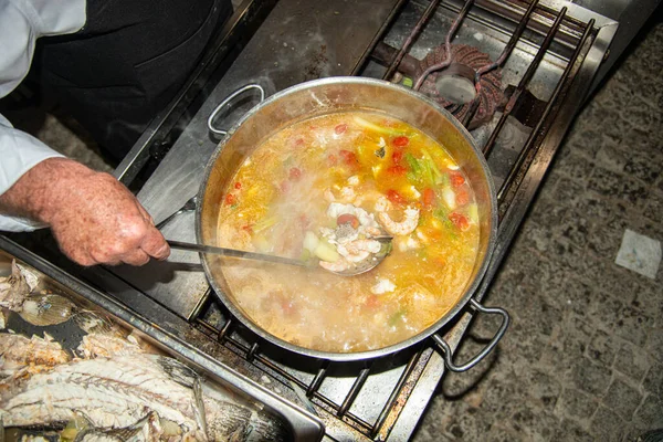 Sopa de peixe à base de grupador fumegante com camarões, mexilhões de água salgada, mini tomates, aipo e cebola. Conceito de cozinha grega. — Fotografia de Stock