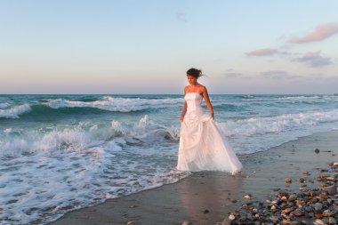 Genç gelin sahilde yalnız yürüyerek gece karanlığında sahiptir.