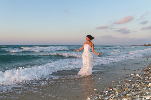 Young bride enjoys a lonesome walk on the beach at dusk — Stock Photo, Image