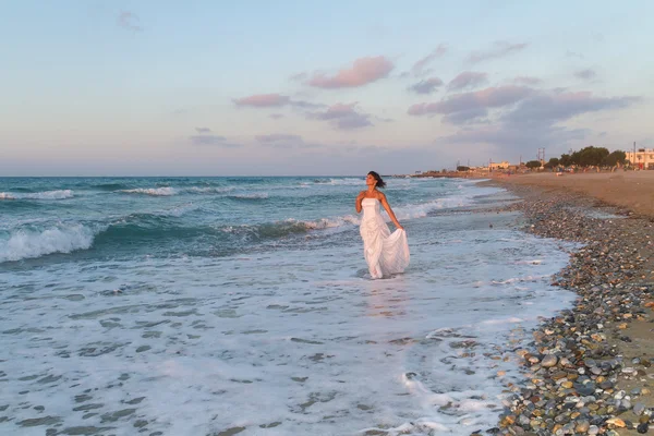 Young bride enjoys a lonesome walk on the beach at dusk — Stock Photo, Image