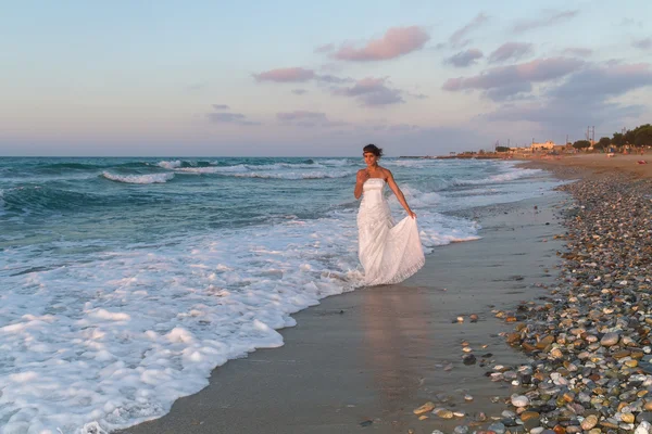 Young bride enjoys a lonesome walk on the beach at dusk — Stock Photo, Image