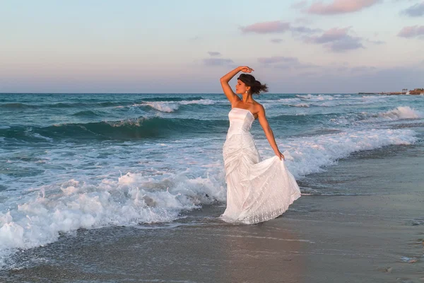 Young bride enjoys a lonesome walk on the beach at dusk — Stock Photo, Image