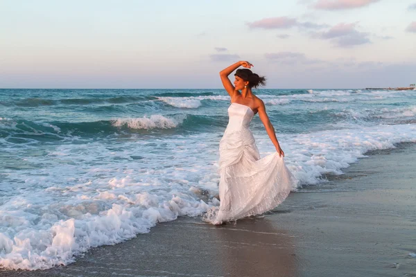 Young bride enjoys a lonesome walk on the beach at dusk — Stock Photo, Image