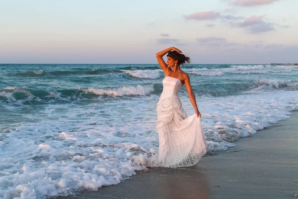 Young bride enjoys a lonesome walk on the beach at dusk — Stock Photo, Image