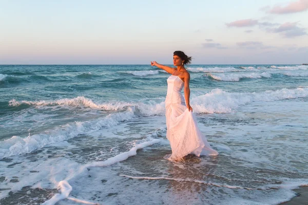 Young bride enjoys a lonesome walk on the beach at dusk — Stock Photo, Image