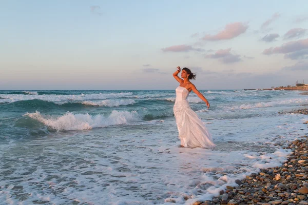 Jeune mariée jouit d'une promenade solitaire sur la plage au crépuscule Photo De Stock