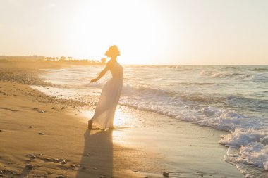 Gece karanlığında puslu bir kumsalda yürüyen genç bir kadın sahiptir.