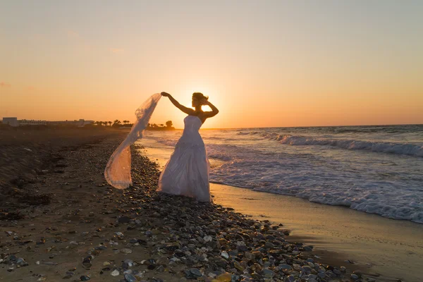 Young bride enjoys walking on a hazy beach at dusk. — Stock Photo, Image