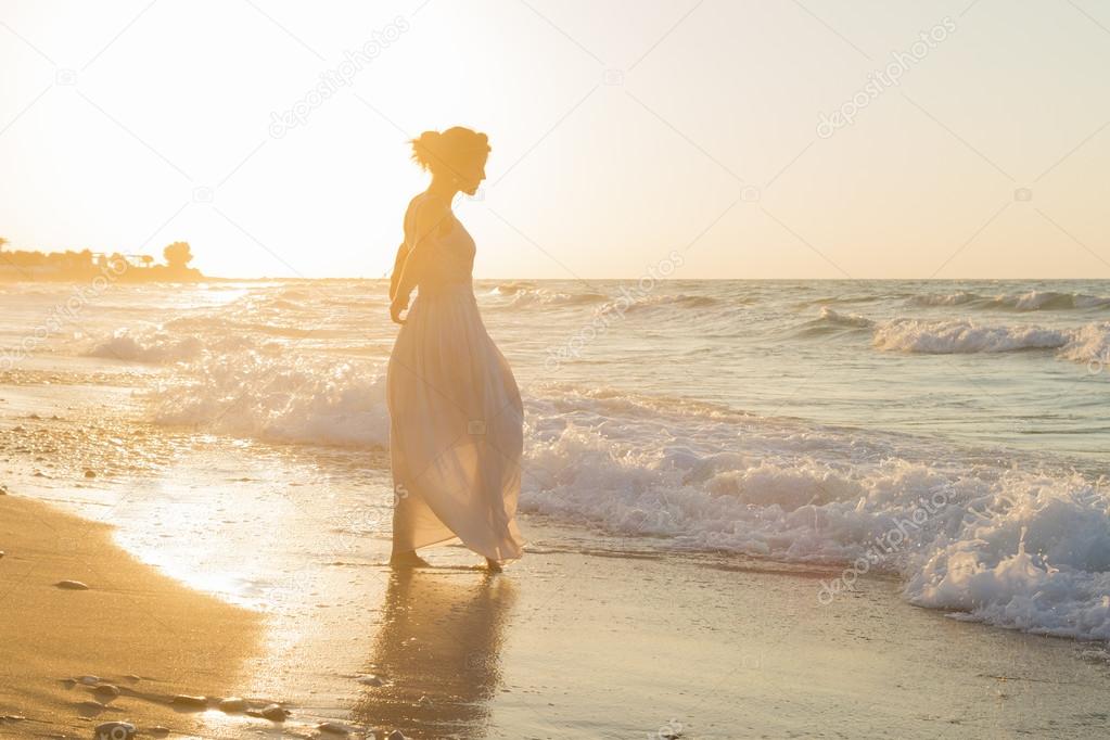 Young woman enjoys walking on a hazy beach at dusk.