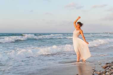 Young woman enjoys a lonesome walk on the beach at dusk.