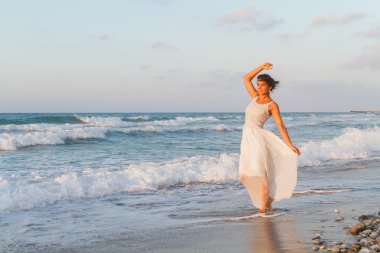Young woman enjoys a lonesome walk on the beach at dusk.