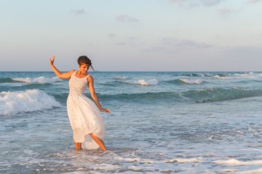 Young woman enjoys a lonesome walk on the beach at dusk.