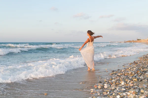 Young woman enjoys a lonesome walk on the beach at dusk.