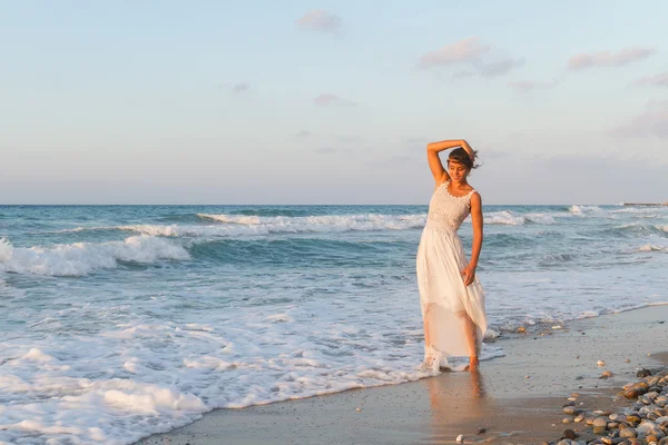 Young woman enjoys a lonesome walk on the beach at dusk. — Stok fotoğraf