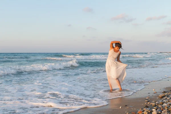 Young woman enjoys a lonesome walk on the beach at dusk.
