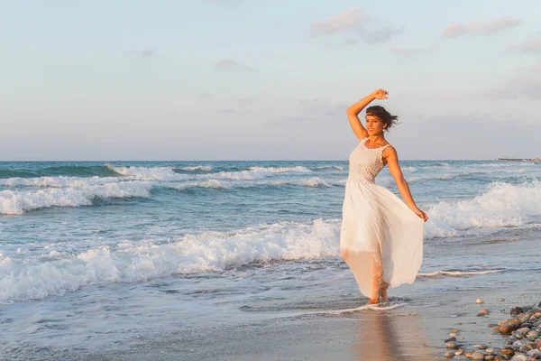 Young woman enjoys a lonesome walk on the beach at dusk. — Stockfoto