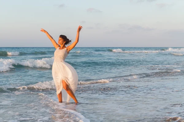 Young woman enjoys a lonesome walk on the beach at dusk. — Stockfoto