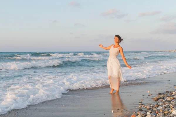 Young woman enjoys a lonesome walk on the beach at dusk. — Stok fotoğraf