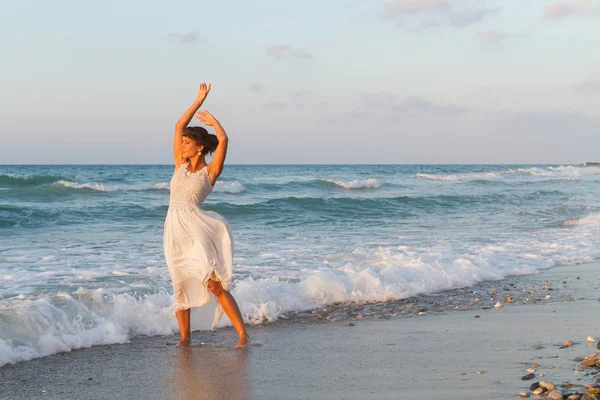 Young woman enjoys a lonesome walk on the beach at dusk. — Stockfoto