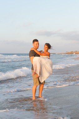 Genç çift gece karanlığında puslu bir sahilde yürüyüş sahiptir.