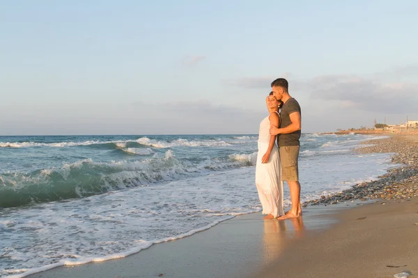 Giovane coppia gode di camminare su una spiaggia nebbiosa al tramonto . — Foto Stock