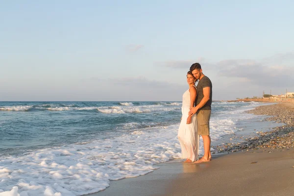 Pareja joven disfruta caminando en una playa nebulosa al atardecer . —  Fotos de Stock