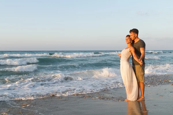 Giovane coppia gode di camminare su una spiaggia nebbiosa al tramonto . — Foto Stock