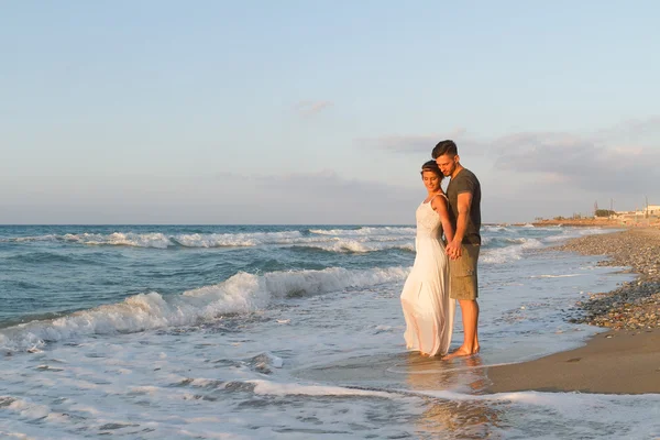 Giovane coppia gode di camminare su una spiaggia nebbiosa al tramonto . — Foto Stock