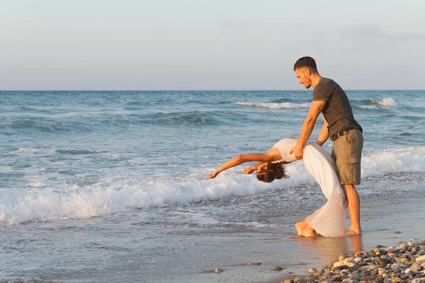 Giovane coppia gode di camminare su una spiaggia nebbiosa al tramonto . — Foto Stock