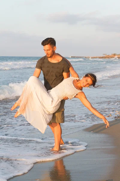 Giovane coppia gode di camminare su una spiaggia nebbiosa al tramonto . — Foto Stock