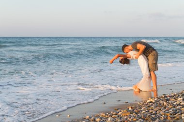 Genç çift gece karanlığında puslu bir sahilde yürüyüş sahiptir.