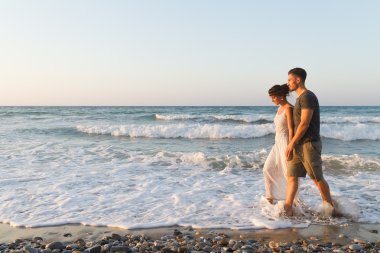 Genç çift gece karanlığında puslu bir sahilde yürüyüş sahiptir.